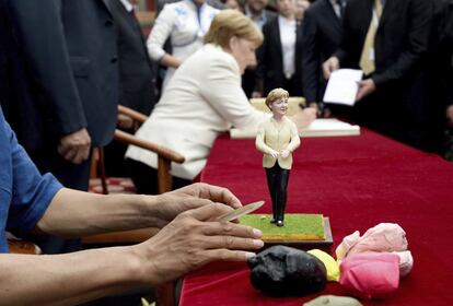 La canciller alemana, Angela Merkel (al fondo), escribe en un libro de visitas junto a una figura de sí misma cerca del Palacio Imperial de Shengyan en China.