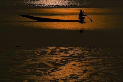 Un pescador rema cerca de una parte congelada del lago Dal durante una puesta de sol en Srinagar, la India.