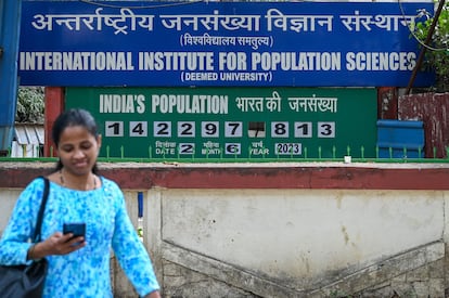 Una mujer pasa ante el contador de población instalado en el exterior del Instituto Internacional de Ciencias de la Población en Bombay, el 2 de junio de 2023. 