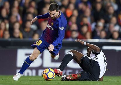 Geoffrey Kondogbia del Valencia intenta evitar el avance del barcelonista Lionel Messi.