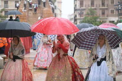 Falleras desfilan en Valencia durante la ofrenda y se protegen con paraguas de la lluvia.