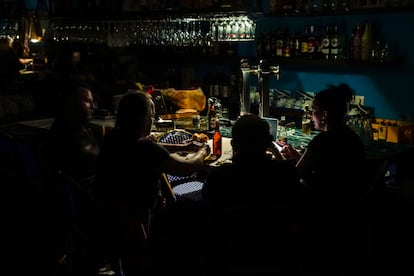 Unas personas toman algo en un bar a semi oscuras en Madrid, este lunes.