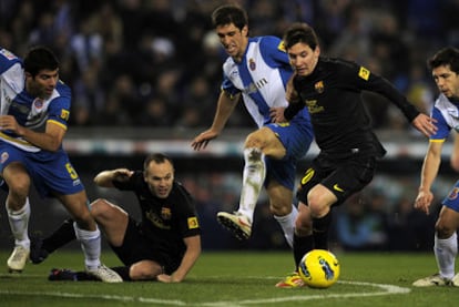 Messi fights for space between Espanyol's Forlín and Javi López, with Iniesta on the floor.