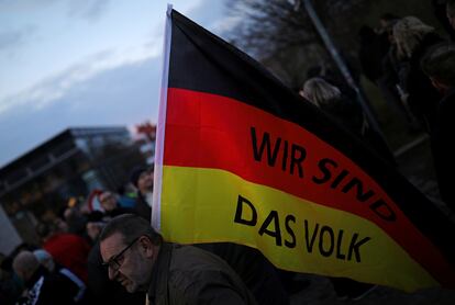 Un simpatizante de AfD lleva una bandera donde se lee "Nosotros somos el pueblo" en una marcha en Erfurt en marzo de 2020.