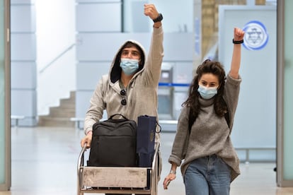 Dos israelíes que regresan a su país muestran las pulseras electrónicas que les han colocado para vigilar su cuarentena, el lunes en el aeropuerto de Tel Aviv.