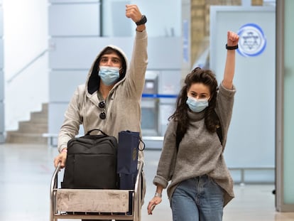 Dos israelíes que regresan a su país muestran las pulseras electrónicas que les han colocado para vigilar su cuarentena, el lunes en el aeropuerto de Tel Aviv.