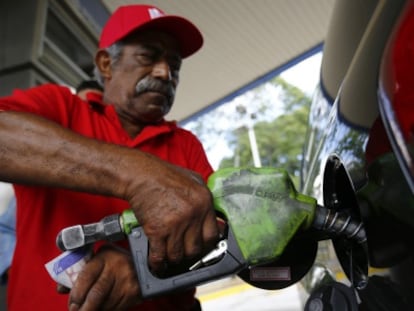 Un hombre llena de combustible un coche en Caracas.