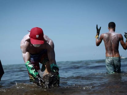 Voluntários retiram óleo na praia de Itapuama, na cidade de Cabo de Santo Agostinho, Pernambuco.