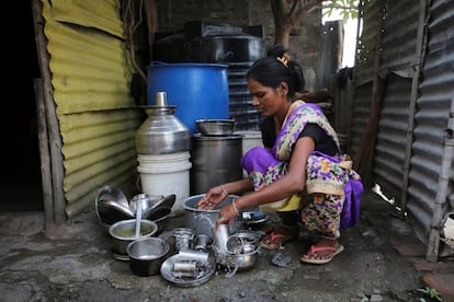 Una mujer lava utensilios en la entrada de su casa en Aurangabad (India).
