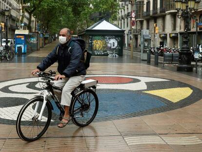 Un hombre protegido con mascarilla pasea en bicicleta por las Ramblas de Barcelona, prácticamente vacías en el quincuagésimo séptimo día del estado de alarma.