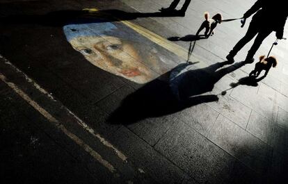 Un viandante pasea por las calles de Roma junto a un dibujo callejero que recrea el cuadro de Vermeer 'La joven de la perla'.