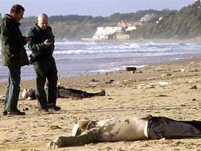 Agentes de la Guardia Civil junto a los cadáveres de dos inmigrantes en la playa de El Buzo, en el Puerto de Santa María.