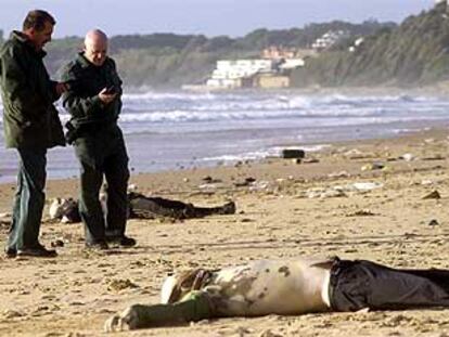 Agentes de la Guardia Civil junto a los cadáveres de dos inmigrantes en la playa de El Buzo, en el Puerto de Santa María.