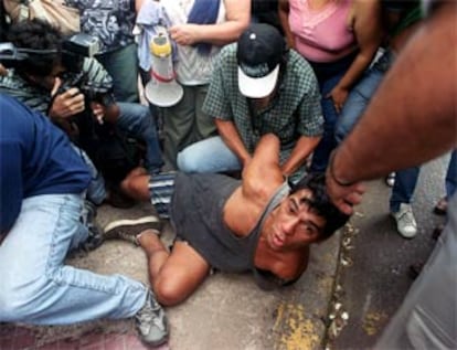 La imagen muestra cómo un policía detiene a un sospechoso de haber saqueado una tienda. Algunos de los que el día antes habían entrado en busca de comida decían: "Estamos recargados de hambre". (AP)