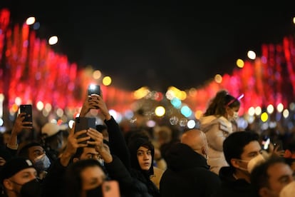 Cientos de personas celebran la víspera de Año Nuevo en la avenida de los Campos Elíseos, en París.