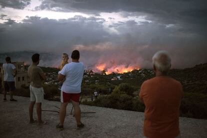 Un grupo de vecinos observa el incendio incontrolado en la ciudad de Rafina (Grecia). 