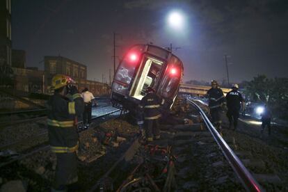 Bomberos inspeccionan uno de los siete vagones que descarrilaron la noche del martes en Filadelfia.