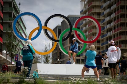 Varios atletas toman imágenes junto a los anillos olímpicos.