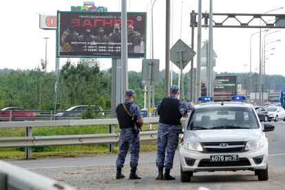 Agentes de policía rusos vigilan una carretera próxima a San Petersburgo con un cartel bajo el lema "Únete a Wagner".