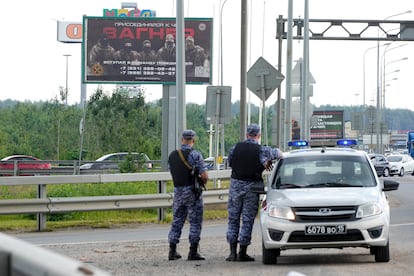 Russian police officers guard a road near St. Petersburg with a sign under the slogan "Join Wagner".