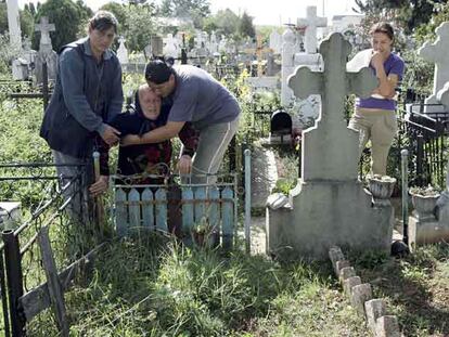 La familia de Marian Milita, en Targoviste. Arriba, sus hermanas sostienen a la madre, Elvira, en el cementerio del pueblo donde quieren enterrarlo, bajo la mirada de Izabela, la hija de Marian. Abajo, en la casa familiar.