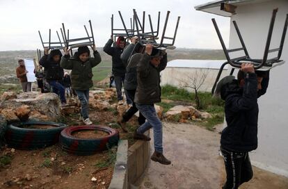 Niños palestinos llevan sillas a una zona abierta después de que las tropas israelíes retiraran la caravana utilizada como aula en la zona de Sosya, al sur de Hebrón (Palestina).