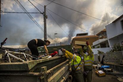 Una vecina del barrio de Todoque, en Los Llanos, es ayudada por empleados municipales a recoger sus pertenencias después de ser evacuada por la cercanía de la lava.