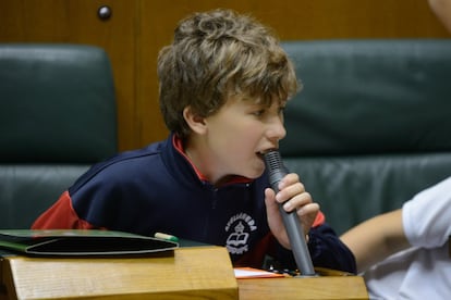 Un niño prueba el micrófono desde su escaño.