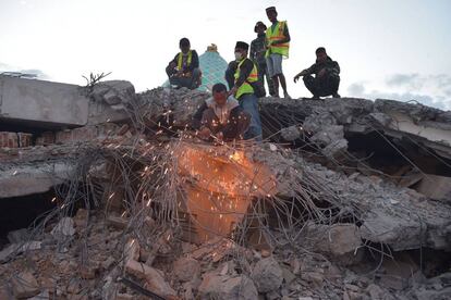 Un voluntario corta barras de hierro destrozadas mientras los miembros de búsqueda y rescate buscan víctimas en los escombros de una mezquita en Pemenang.