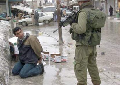 Un soldado israelí vigila a un palestino detenido en el centro de Hebrón.