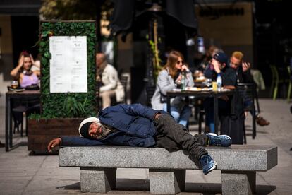 Un persona sin hogar junto a las terrazas de la plaza de Santa Ana, en Madrid.