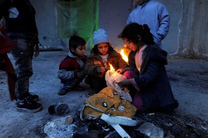 Una familia de sirios evacuados de la zona orienta de Alepo encienden un fuego para calentarse usando bolsas de plástico, dentro de un refugio en el área controlada por el gobierno de Jibreen en Alepo el 30 de noviembre.