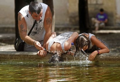 Varios turistas se refrescan en el centro de C&oacute;rdoba.