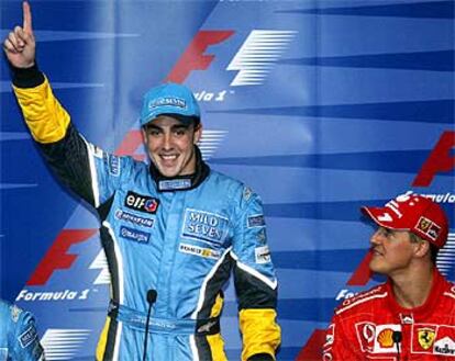 Alonso levanta el dedo índice en la conferencia de prensa ante la mirada de Schumacher.