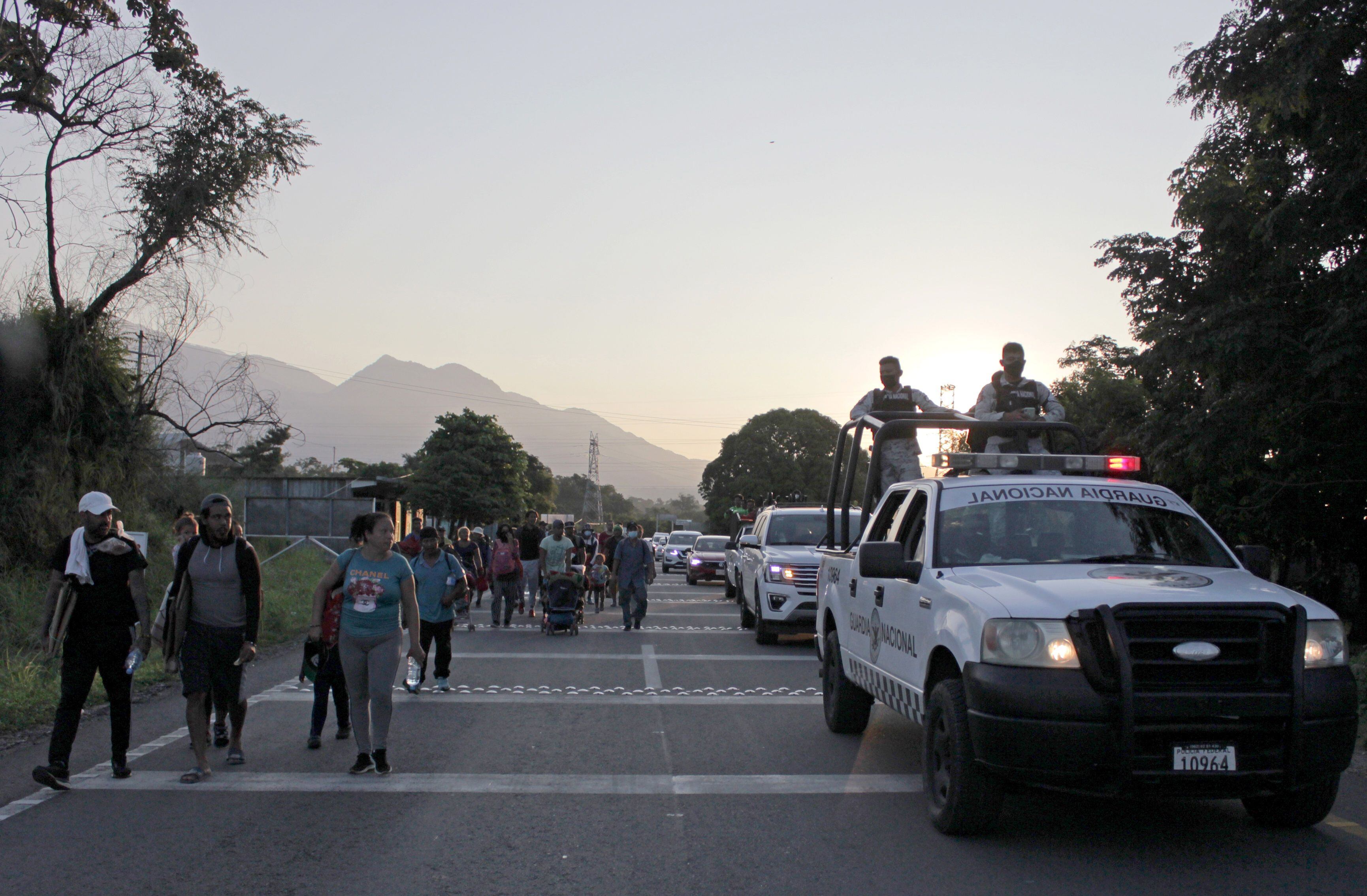 Migrantes caminan en caravana en el Estado de Chiapas mientras son escoltados por miembros de la Guardia Nacional.