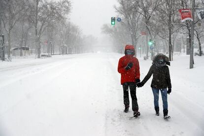 Dos personas caminan por el Paseo de la Castellana. 