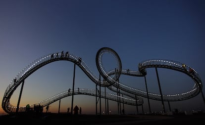 Varias personas recorren la escultura gigante <i>Tigre y Tortuga</i>, en Duisburg (Alemania). Con forma de montaña rusa, sus 249 escalones pueden ser recorridos por 40 visitantes a la vez, elevándose hasta una altura de 85 metros sobre la región del Ruhr desde la colina Heinrich-Hildebrand-Hoeh donde está situada, en pleno parque de Angerpark.