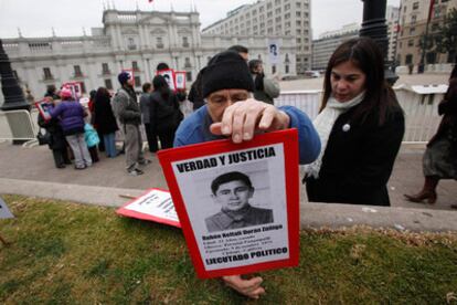 Un activista de los derechos humanos coloca un cartel con la foto de uno de los desaparecidos durante la dictadura de Pinochet frente al palacio presidencial.