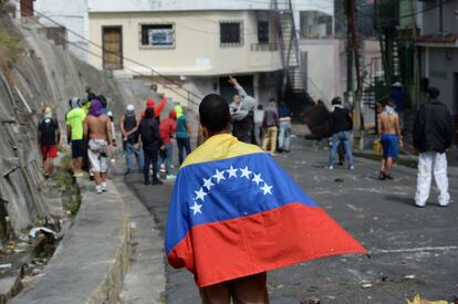 Un asistente a las protestas envuelto en una bandera nacional venezolana