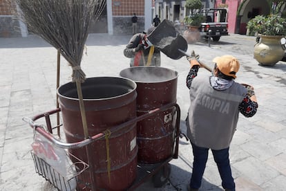 Debido a la contingencia activada por la caída de ceniza, al menos 40 municipios de Puebla, aledaños al volcán, tendrán clases a distancia. Las autoridades han pedido a las comunidades estar alertas ante cualquier indicación de Protección Civil. En la imagen, dos empleados de limpia depositan la ceniza volcánica en un contenedor, en Atlixco.