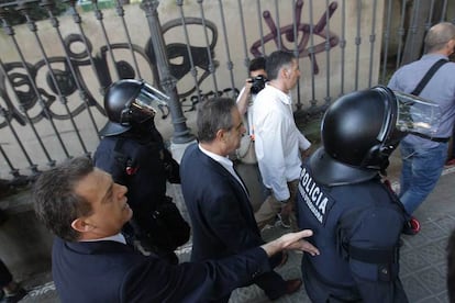 El diputado socialista Celestino Corbacho acude al Parlament fuertemente escoltado por agentes de la Policía Nacional, ante los abucheos de los manifestantes.