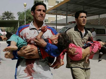 Dos iraquíes corren con unos niños heridos en brazos para llevarles al hospital en Ciudad Sáder, en Bagdad.