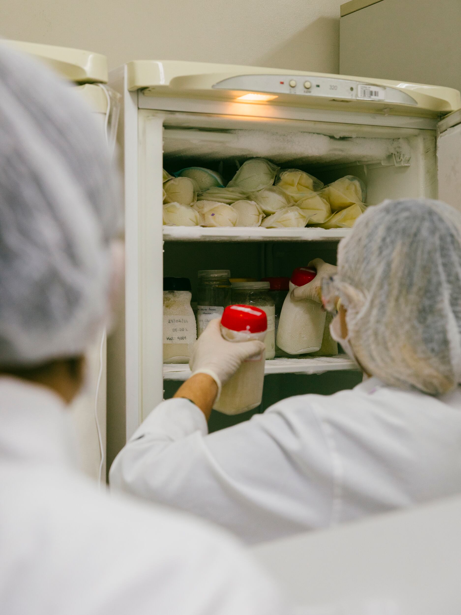 Un auxiliar de laboratorio ordena los envases de leche materna extraída para que puedan someterse a un proceso de control de calidad.