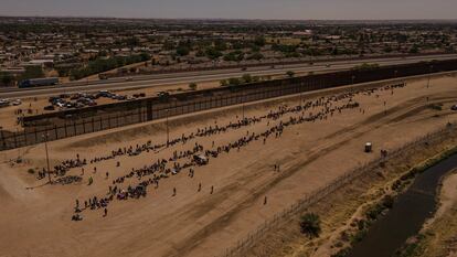 Cientos de migrantes esperan cerca del muro fronterizo, después de cruzar el río Bravo, en Ciudad Juárez.