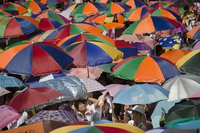 Los manifestantes se protegen del sol durante las protestas en la intersección de Ratchaprasong, en Bangkok. Miles de manifestantes antigubernamentales bloquearon decenas de avenidas en Bangkok con el objetivo de forzar la dimisión del Gobierno interino de Yingluck Shinawatra y suspender las elecciones de febrero.