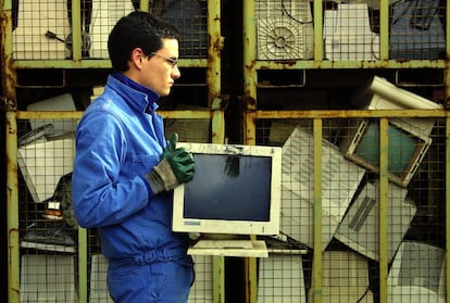 Un operario traslada un viejo monitor de ordenador en la empresa vasca de reciclaje de chatarra tecnológica Indumetal Recycling.