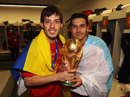 Silva, con la bandera de Las Palmas, y Pedro con la de Tenerife, sostienen la Copa del Mundo conseguida por España en Sudáfrica 2010.