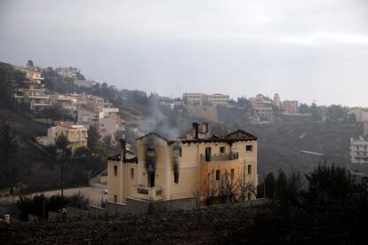 Una casa continua desprenent fum després del pas de l'incendi per Neos Voutzas (Grècia).