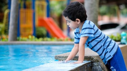 Un niño en el bordillo de una pisicina. 