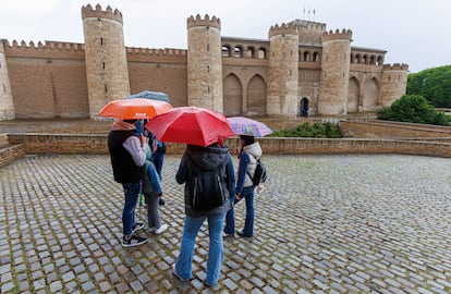 Turistas a las puertas del palacio de La Aljaferia se protegen de un chaparrón, el pasado viernes en Zaragoza. 